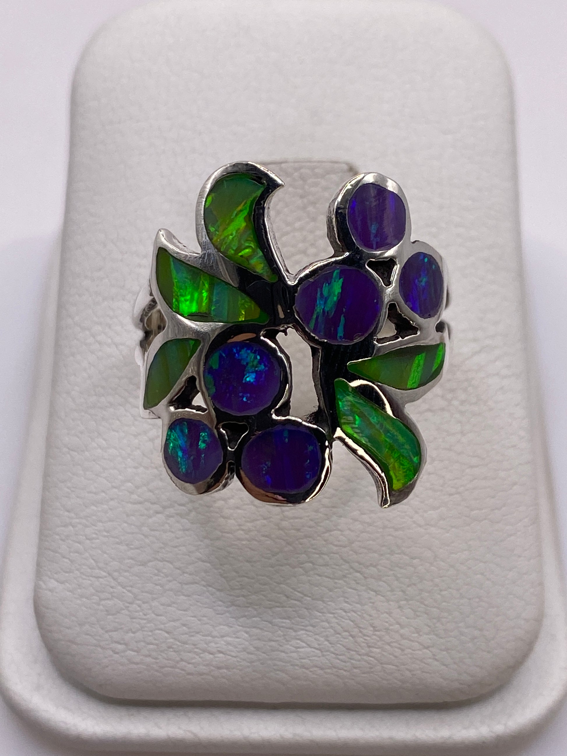 Anillo de plata con ópalo de fuego verde y púrpura en la mano de una mujer