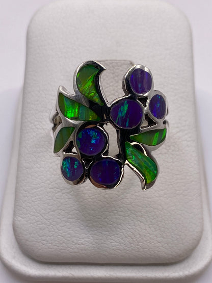 Anillo de plata con ópalo de fuego verde y púrpura en la mano de una mujer