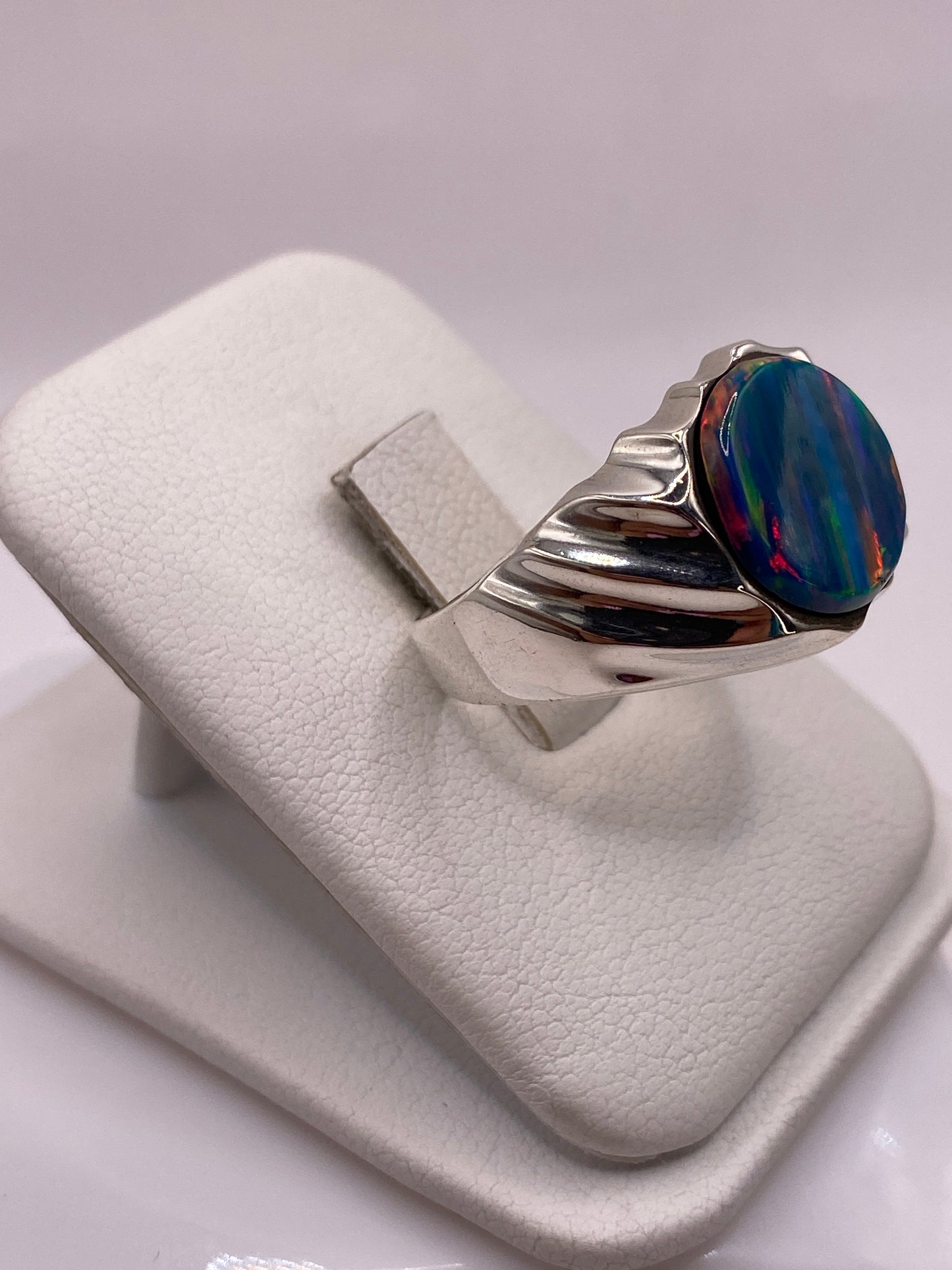 Vista lateral del anillo macizo con piedra de fuego en tonos naranja, verde y azul