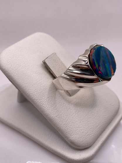 Vista lateral del anillo macizo con piedra de fuego en tonos naranja, verde y azul