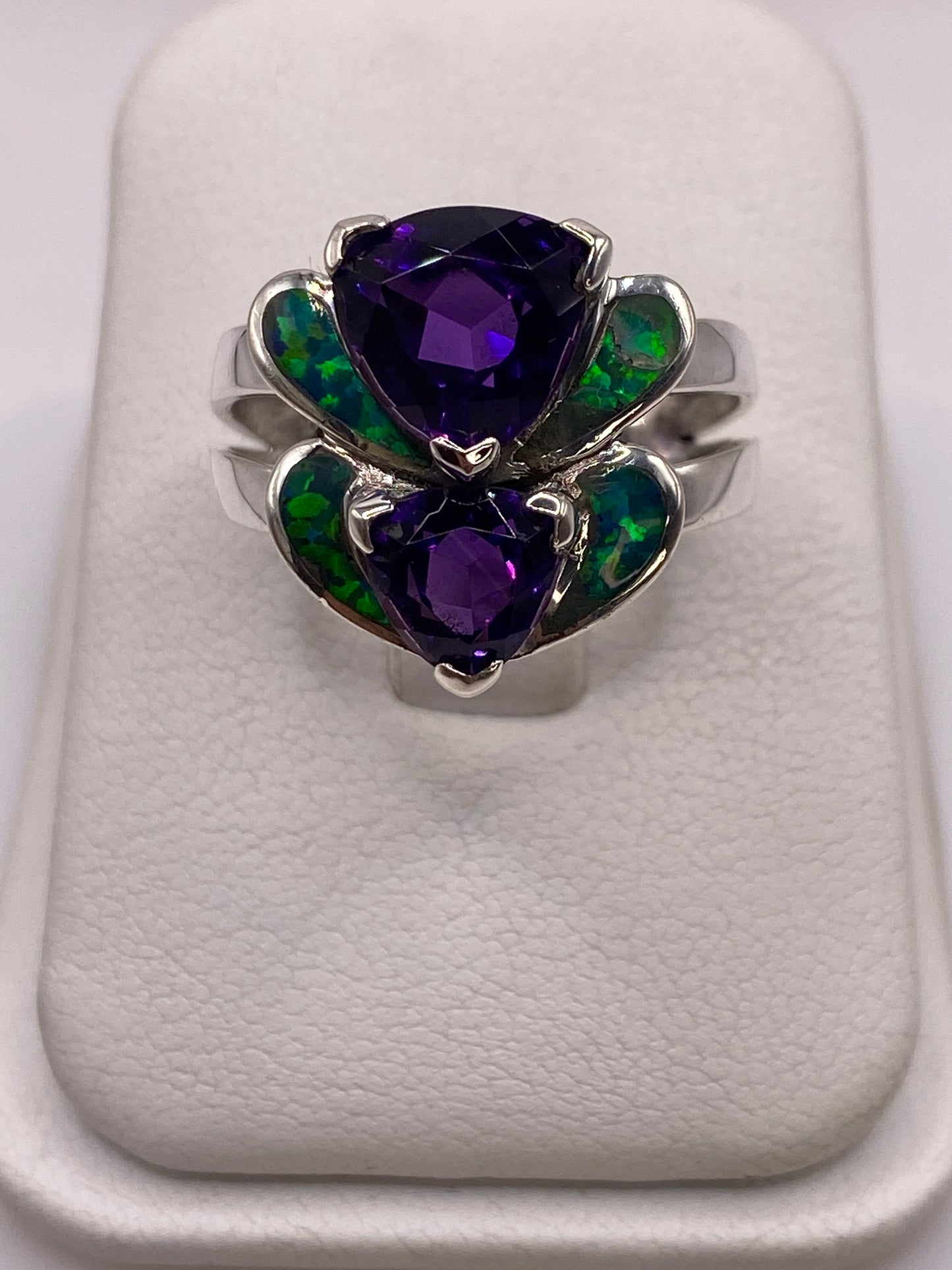Anillo de plata con doble corazón de ópalo de fuego verde iridiscente sobre dedo de mujer