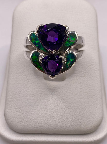 Anillo de plata con doble corazón de ópalo de fuego verde iridiscente sobre dedo de mujer