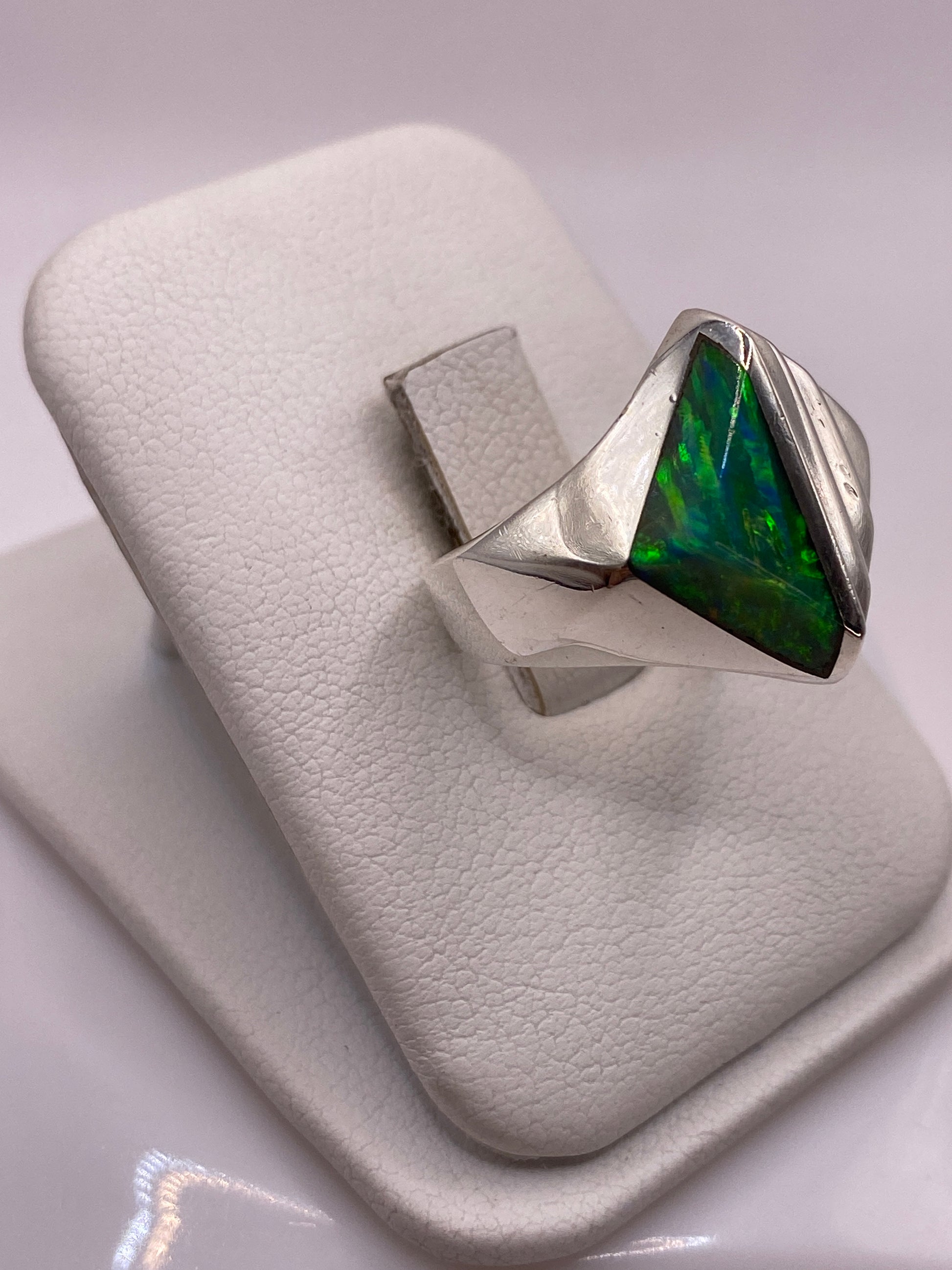 Anillo escultural de plata con banda acanalada y ópalo verde-azul, puesto en dedo