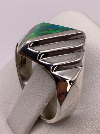 Detalle lateral del anillo mostrando el juego de colores del ópalo y el acanalado pulido