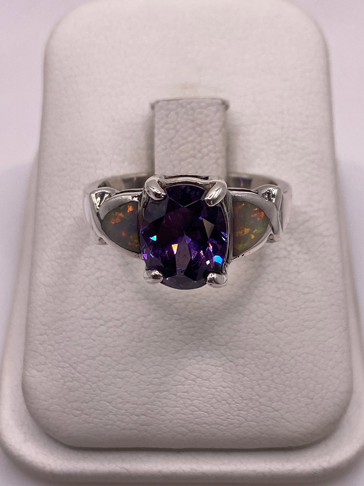 Anillo de plata con ópalo de fuego multicolor mostrando tonos naranja, rojo y verde sobre fondo blanco