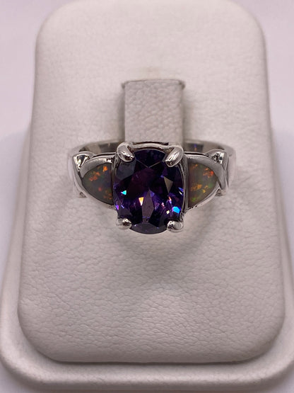Anillo de plata con ópalo de fuego multicolor mostrando tonos naranja, rojo y verde sobre fondo blanco