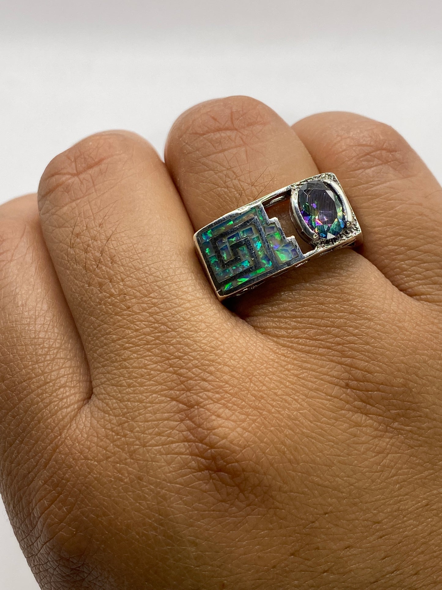 Anillo en la mano mostrando el ópalo de fuego con brillos naturales y la geometría prehispánica integrada