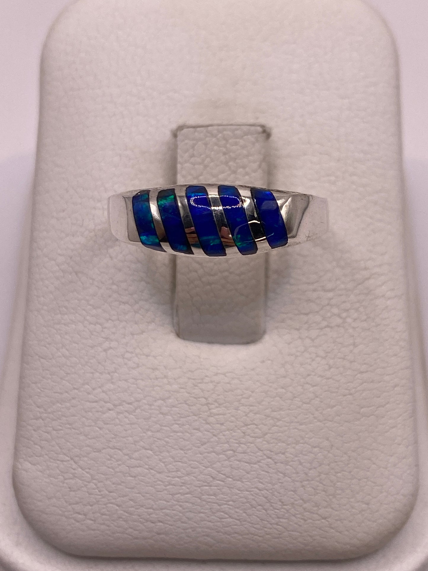 Anillo de plata minimalista con ópalo de fuego azul brillante sobre fondo blanco