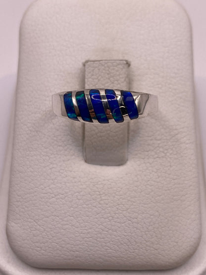 Anillo de plata minimalista con ópalo de fuego azul brillante sobre fondo blanco