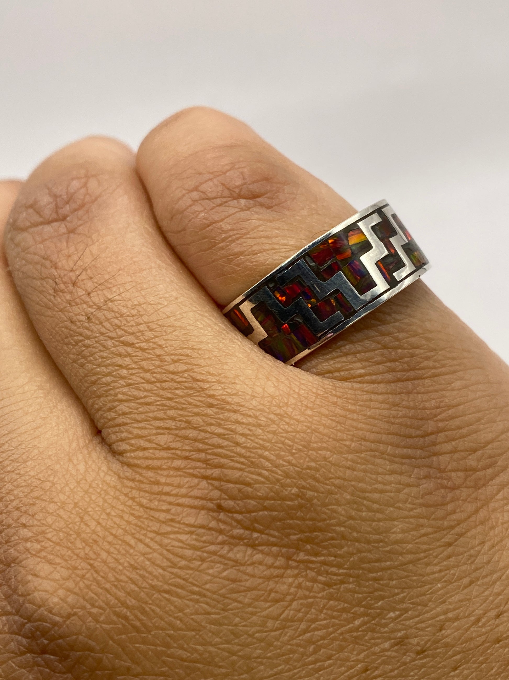 Anillo de ópalo de fuego en mano, exhibiendo el patrón geométrico y la profundidad del color multicolor de la piedra