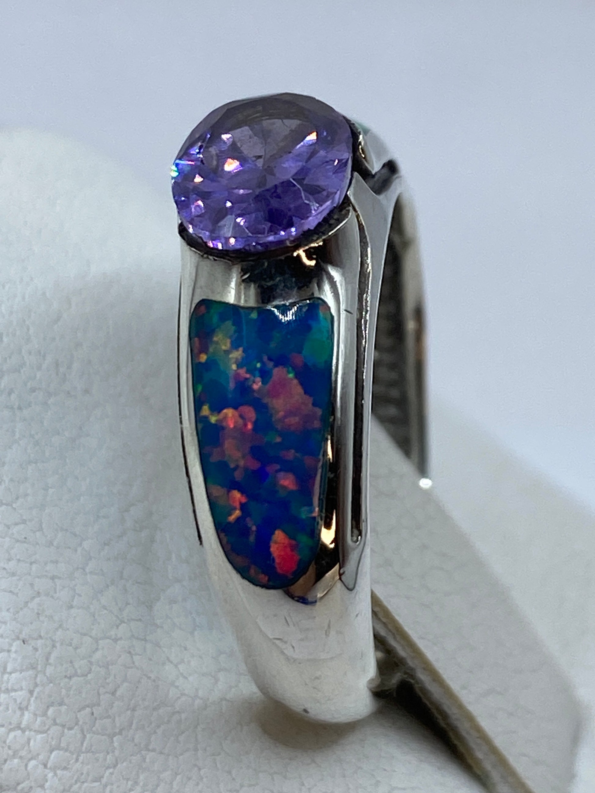 Detalle lateral del anillo en mano femenina, resaltando la banda pulida de 8 mm y el brillo del ópalo