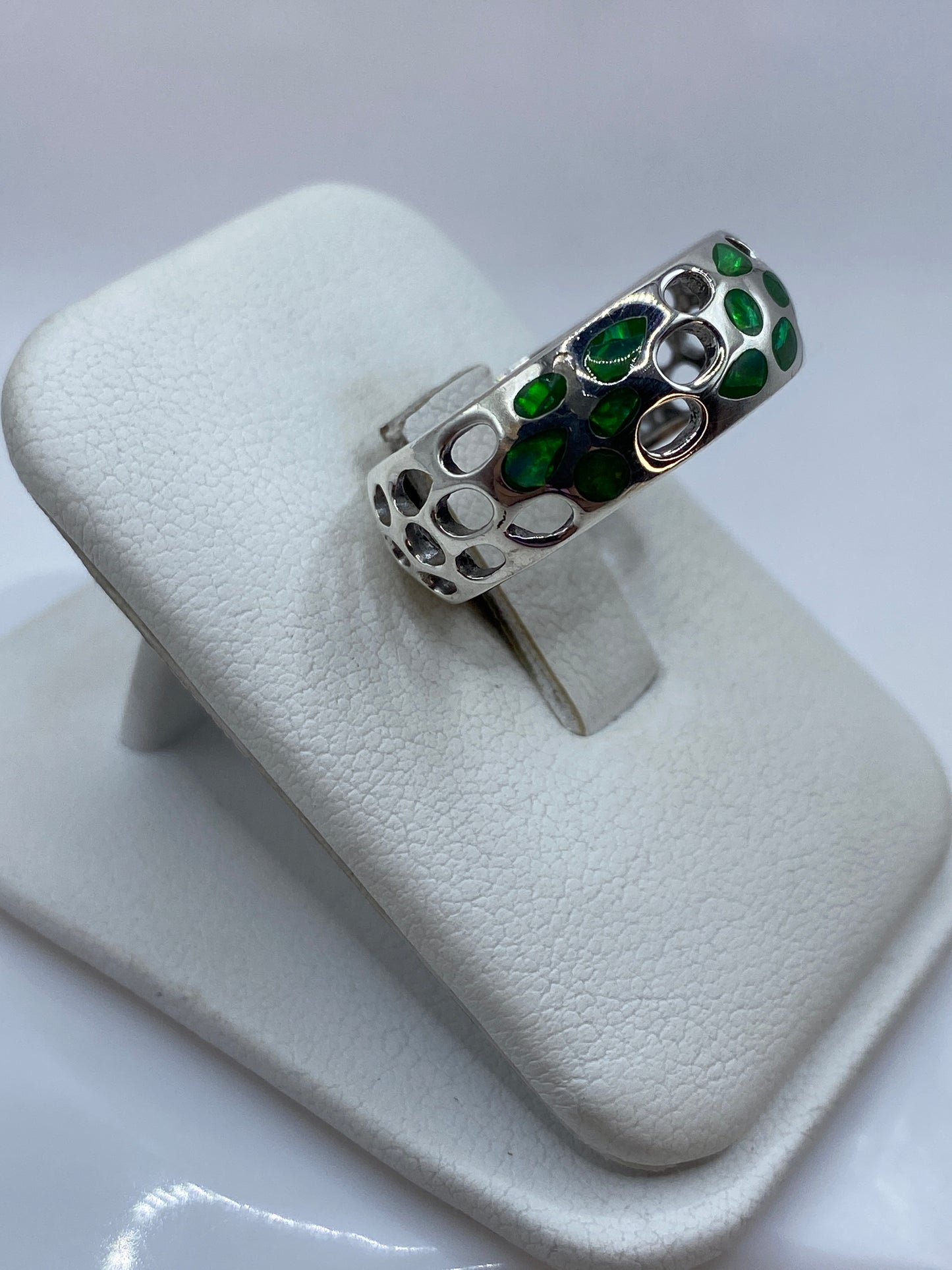 Anillo unisex de plata con ópalo de fuego en la mano, mostrando el juego de colores verde y limón