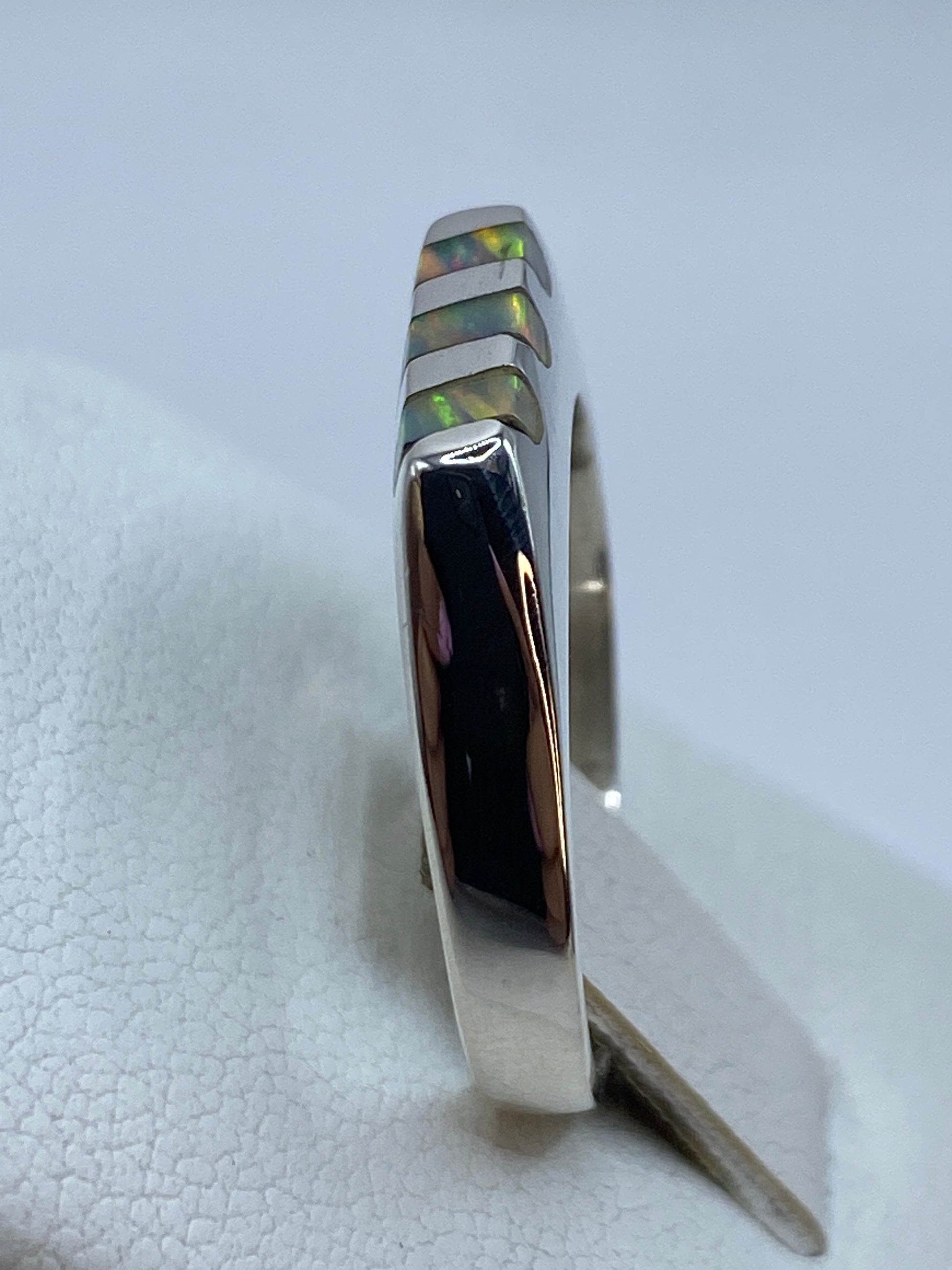 Anillo en la mano mostrando el diseño escalonado y el brillo del ópalo