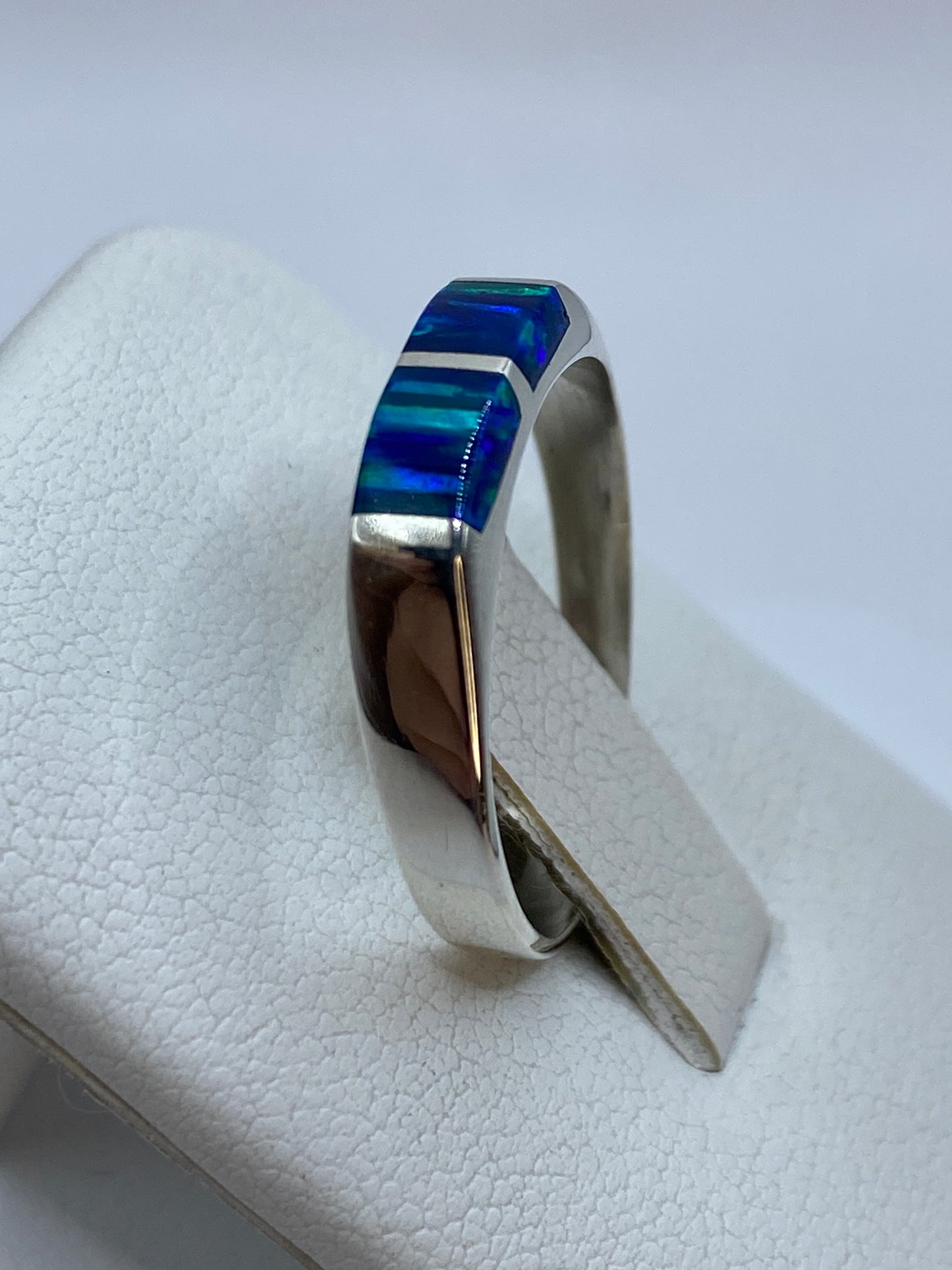Anillo ópalo azul en uso en dedo, mostrando el brillo natural de la piedra