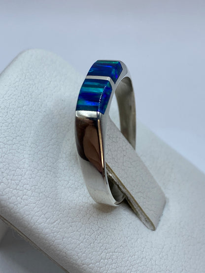 Anillo ópalo azul en uso en dedo, mostrando el brillo natural de la piedra