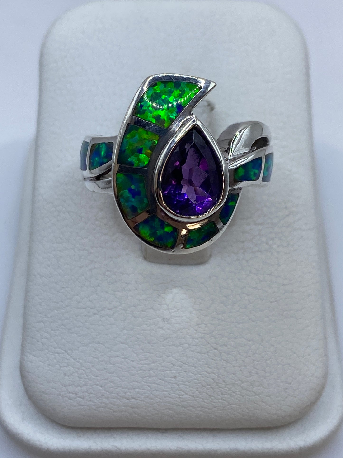 Anillo de plata herradura con ópalo de fuego mostrando colores verdes, azules y púrpuras en el dedo