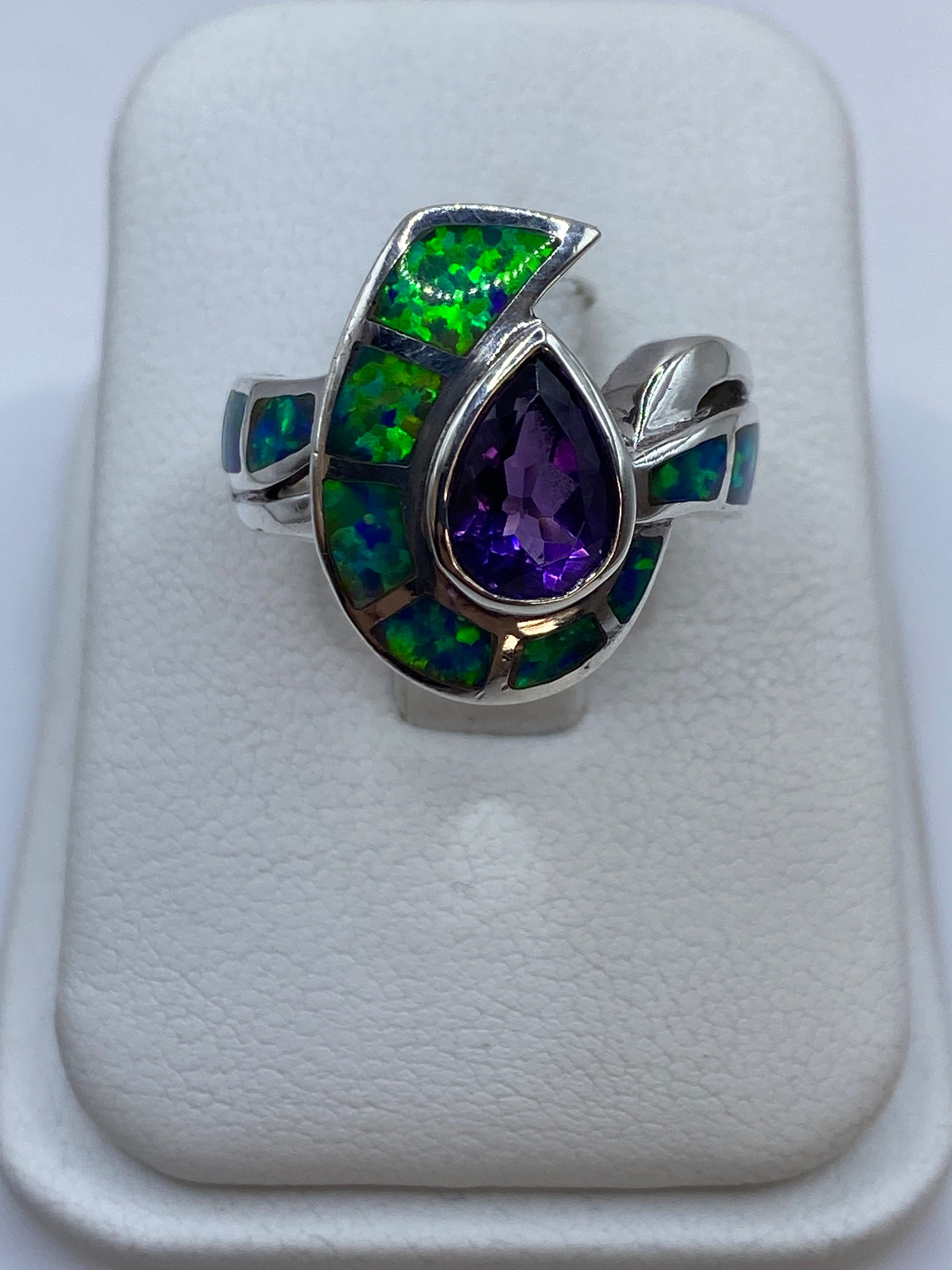 Anillo de plata herradura con ópalo de fuego mostrando colores verdes, azules y púrpuras en el dedo