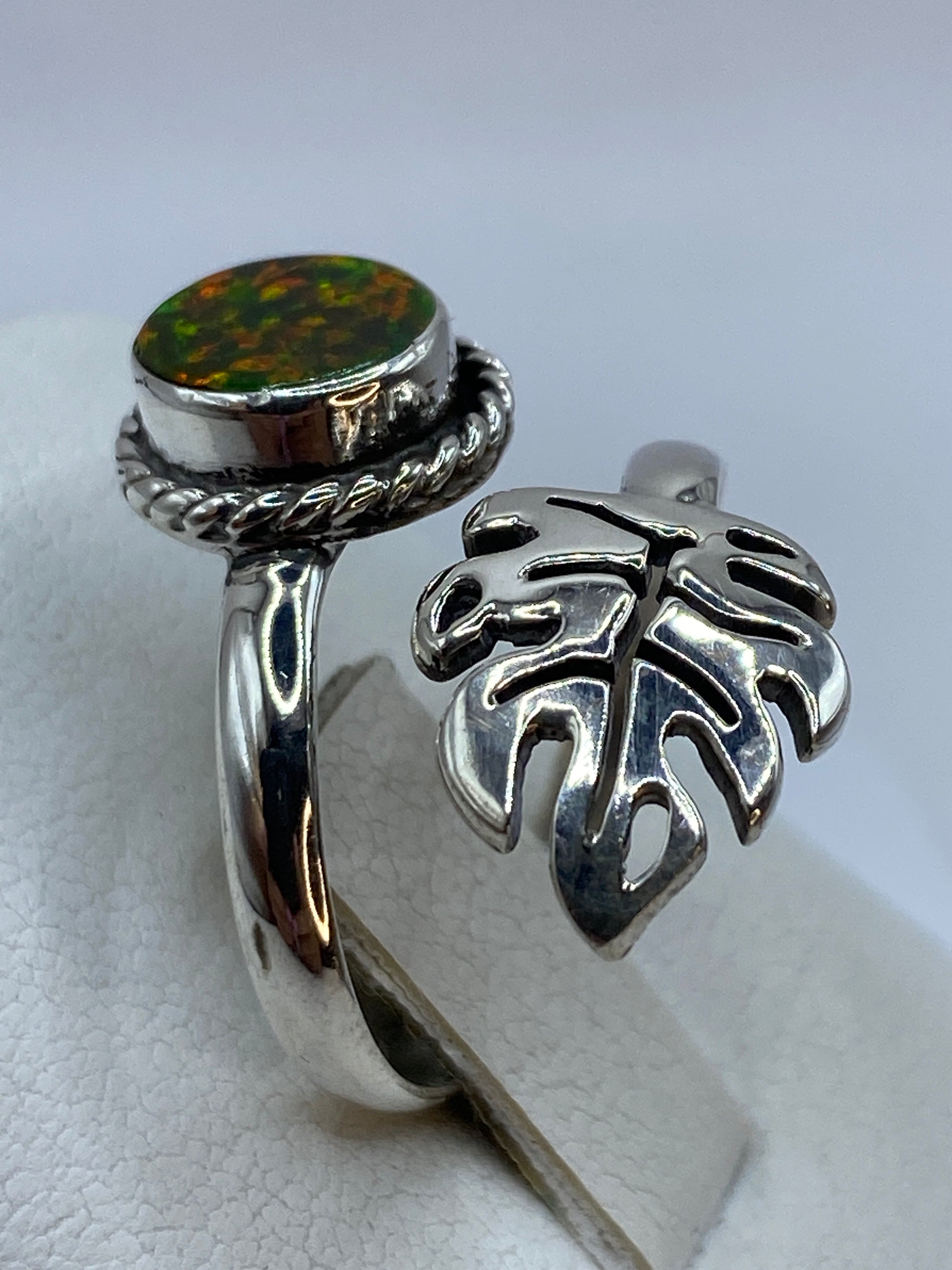 Anillo ajustable ópalo de fuego en la mano de una mujer con uñas decoradas