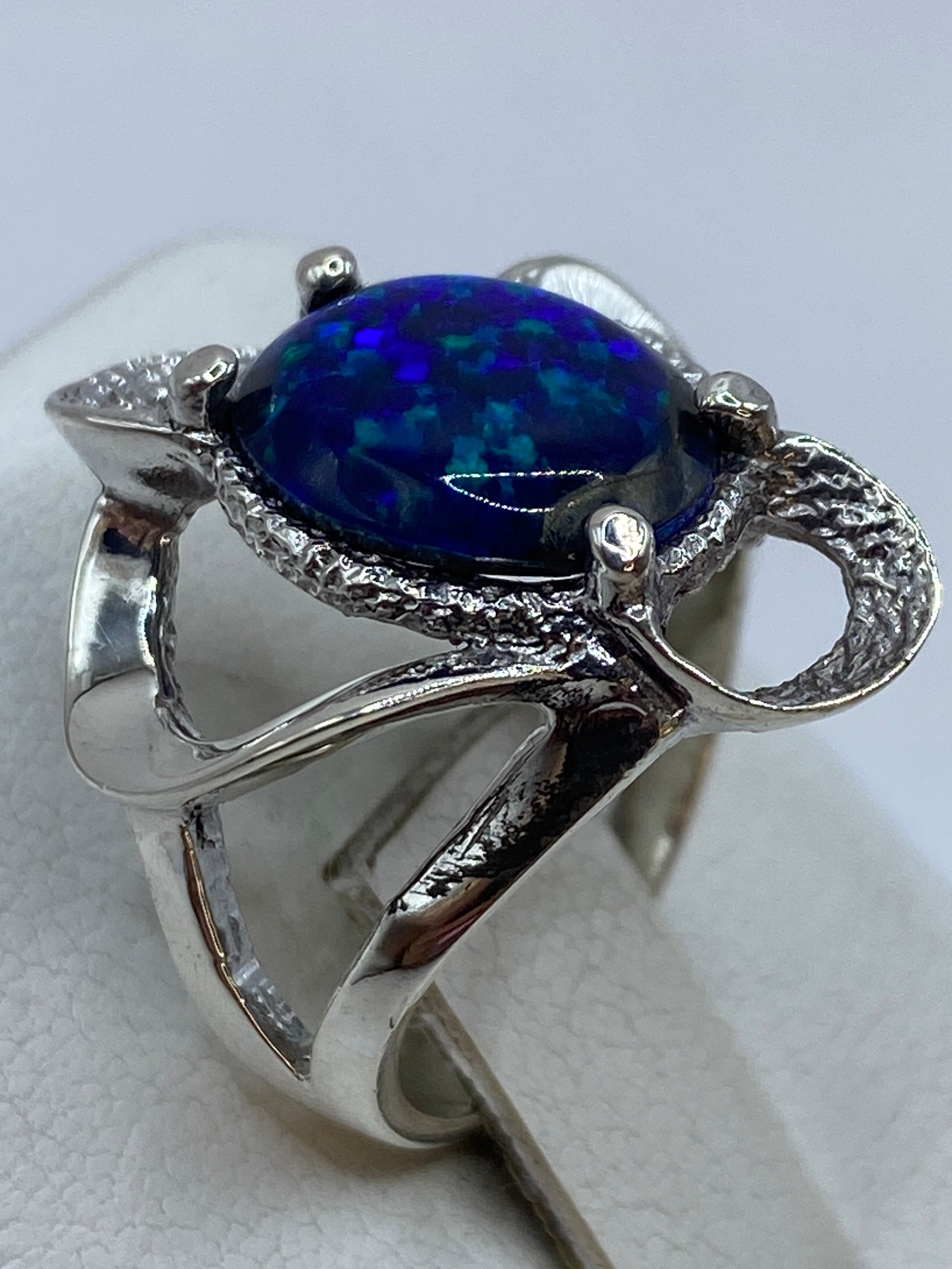Anillo de ópalo azul puesto en mano mostrando el juego de luz natural de la piedra