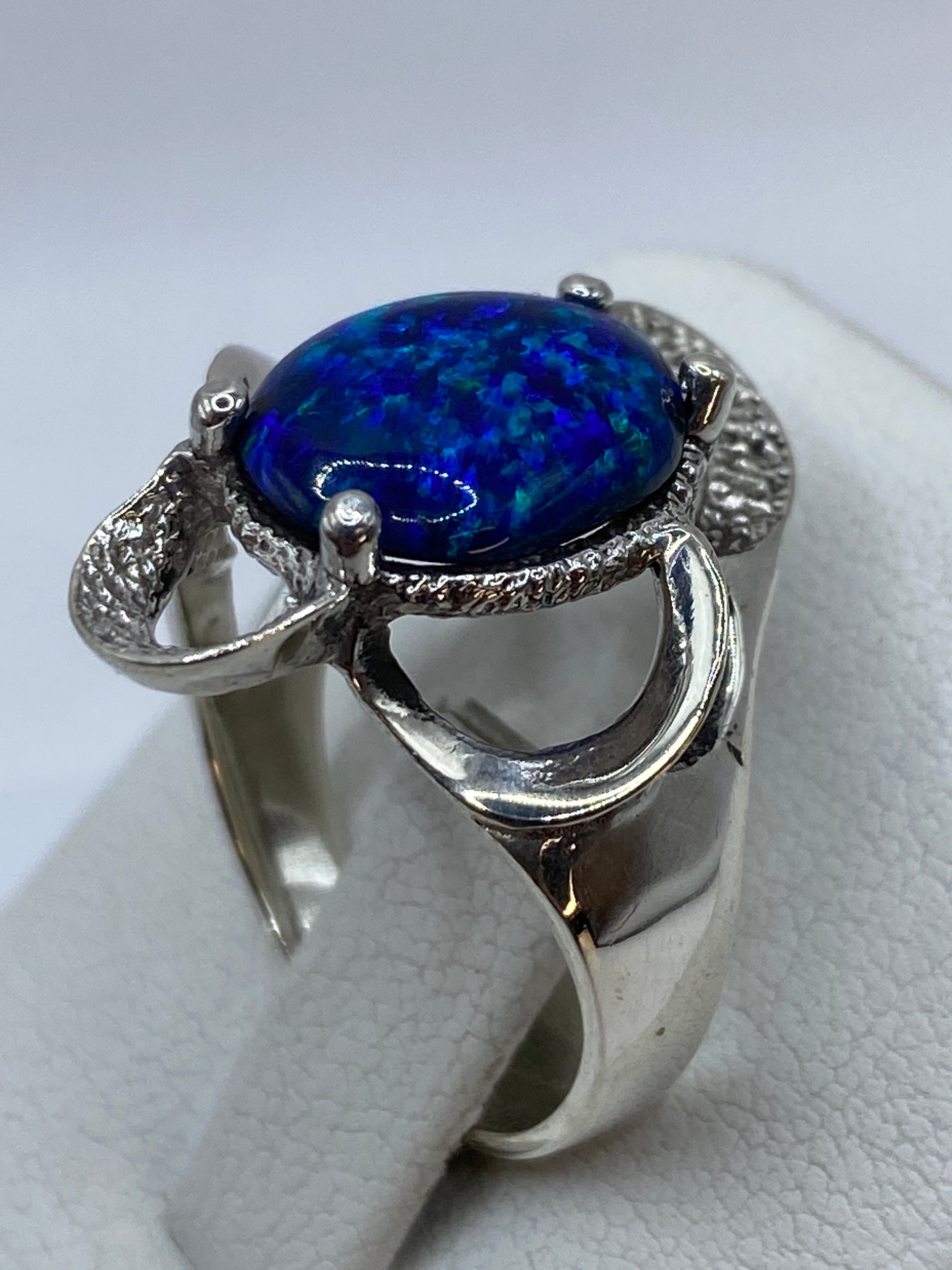 Anillo de plata .950 en la mano mostrando el fuego azul del ópalo y las molduras grabadas