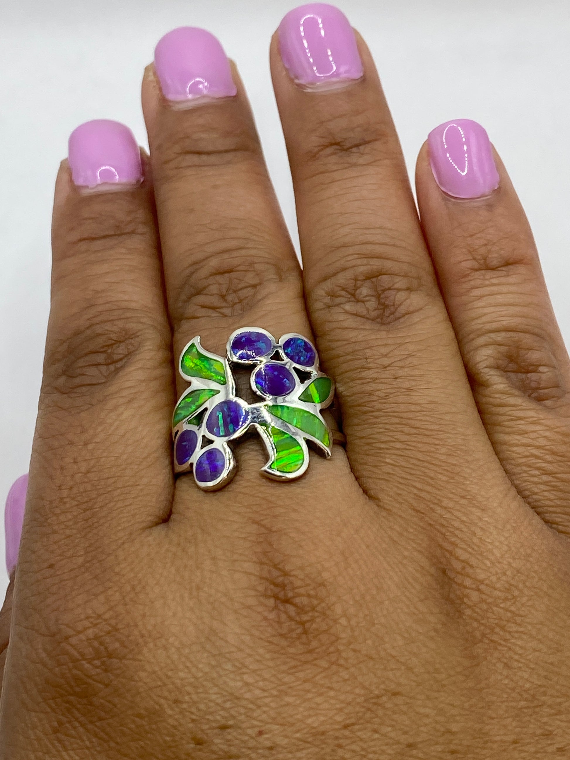 Anillo de ópalo de fuego puesto en mano mostrando el juego de colores morado y verde