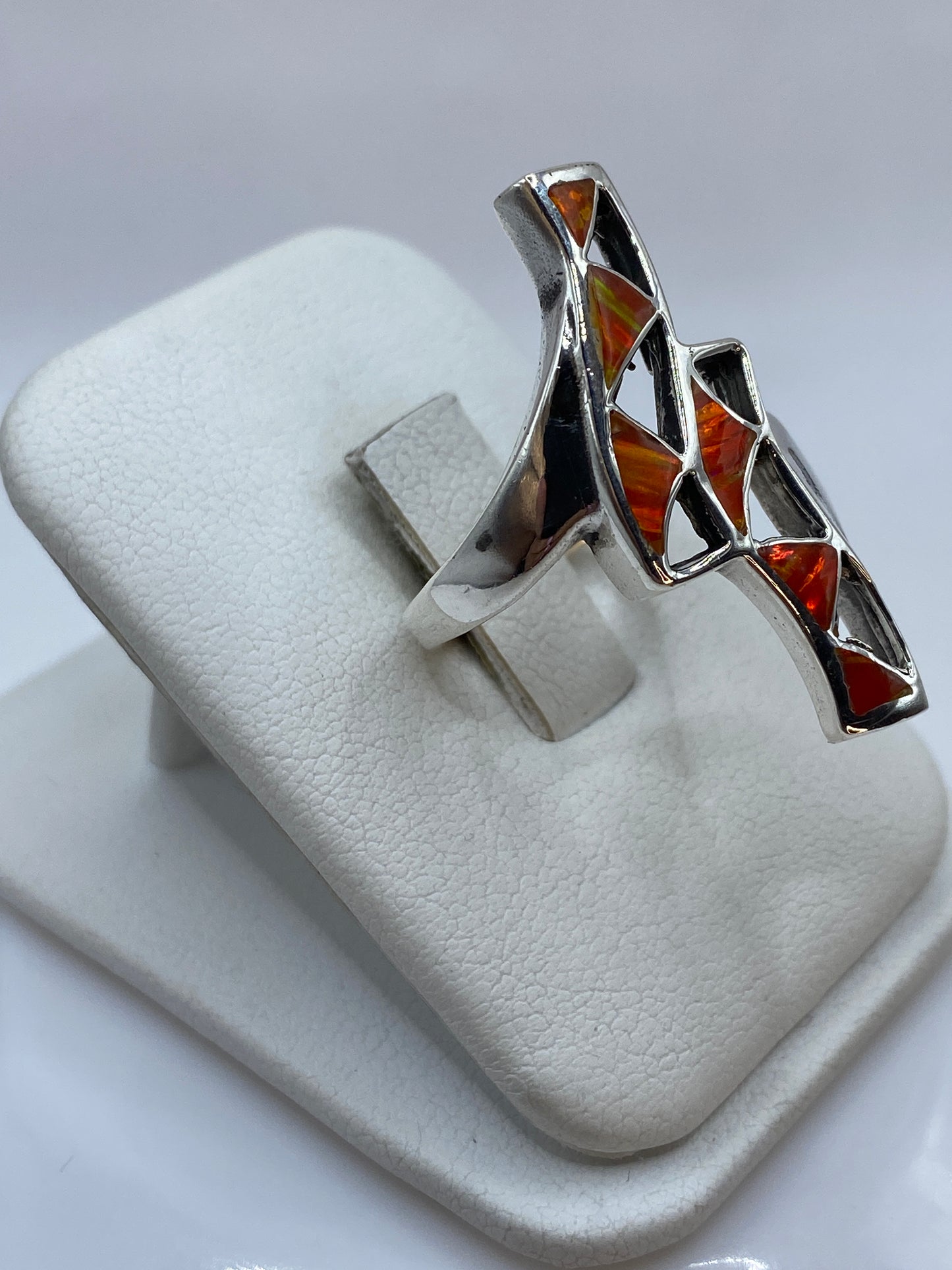 Detalle lateral del anillo mostrando la profundidad del ópalo y el fuego naranja-rojo