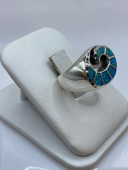 Vista frontal del anillo mostrando el juego cromático azul y verde del ópalo natural
