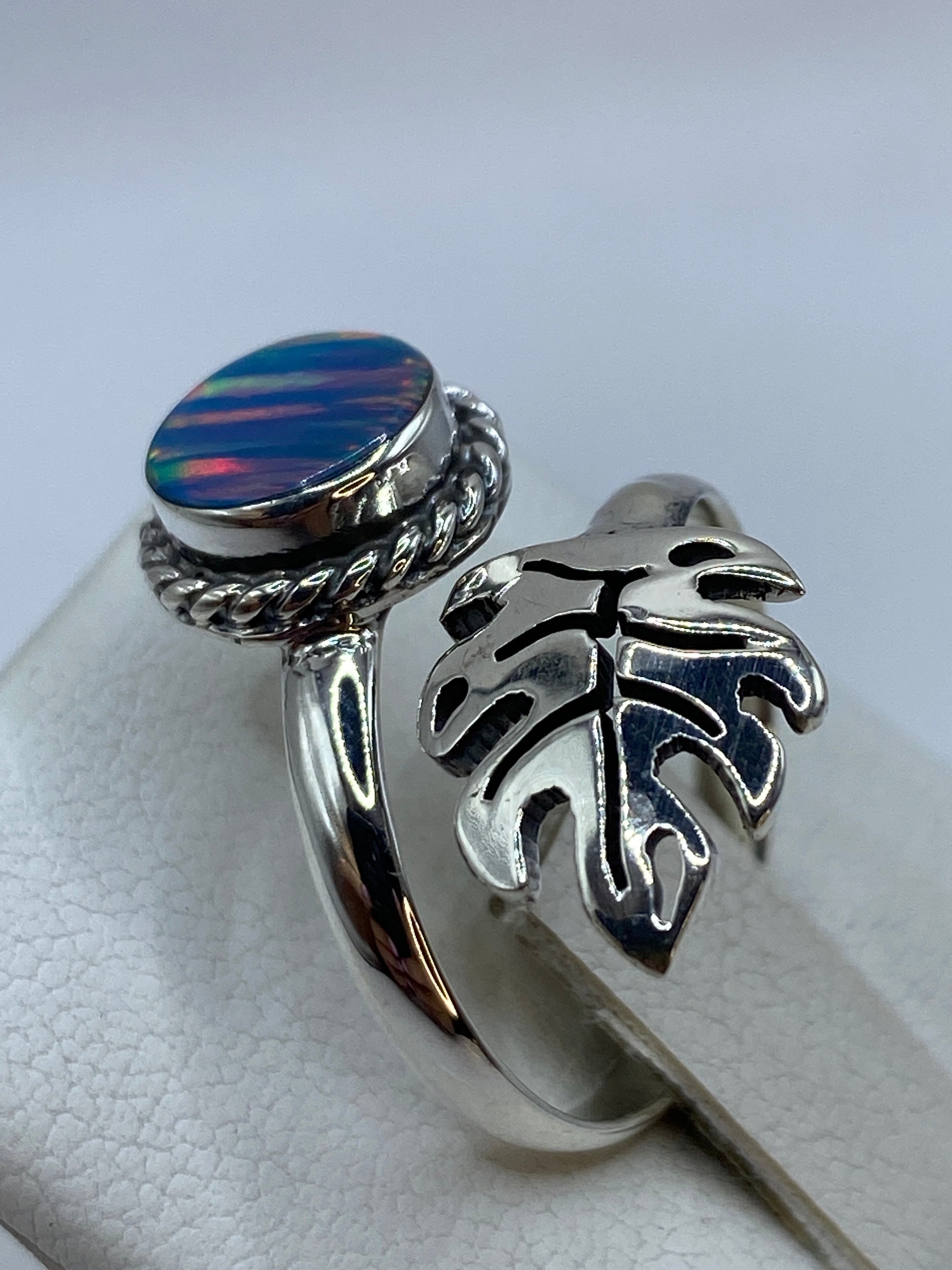 Anillo ajustable de diseño étnico con ópalo azul puesto en dedo, detalle del fuego del ópalo