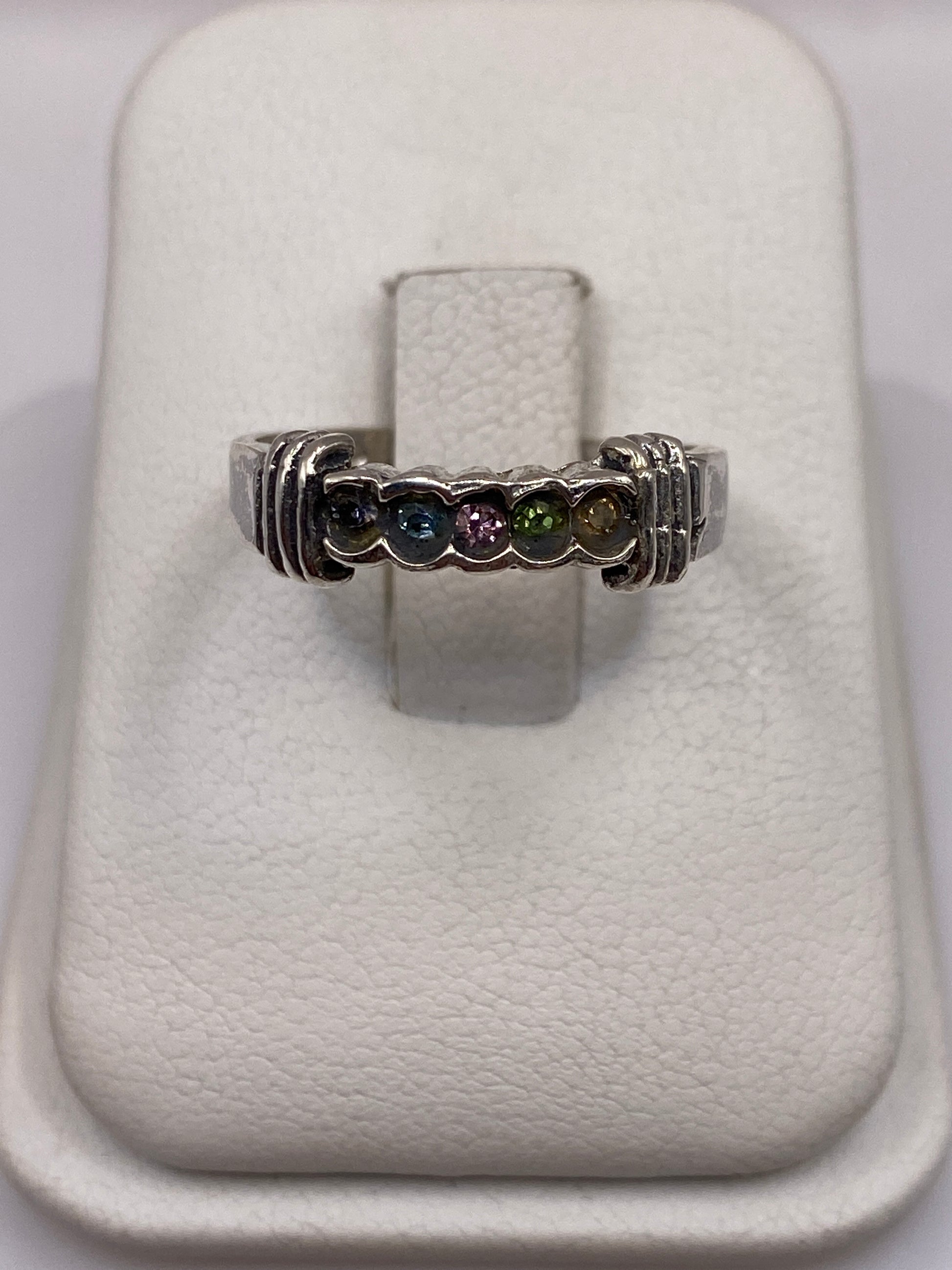 Anillo de plata solitario con circonia multicolor (azul, rosa, verde) en dedo de mujer