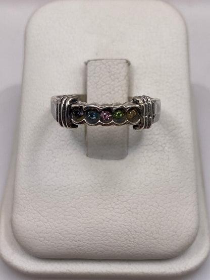Anillo de plata solitario con circonia multicolor (azul, rosa, verde) en dedo de mujer