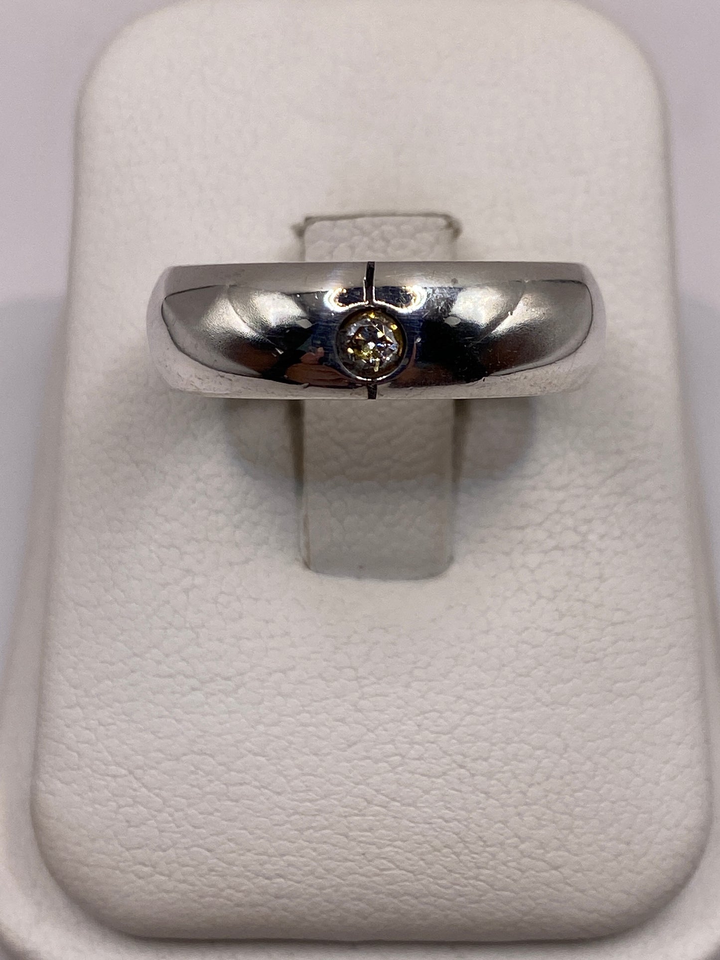 Anillo de plata solitario banda pulida con circonia en la mano de un hombre