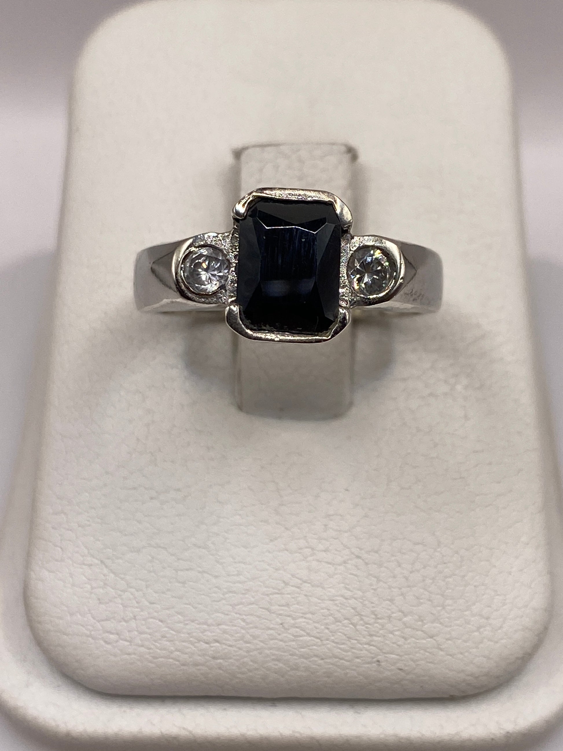 Anillo de plata solitario con circonia negra brillante, vista frontal sobre soporte blanco