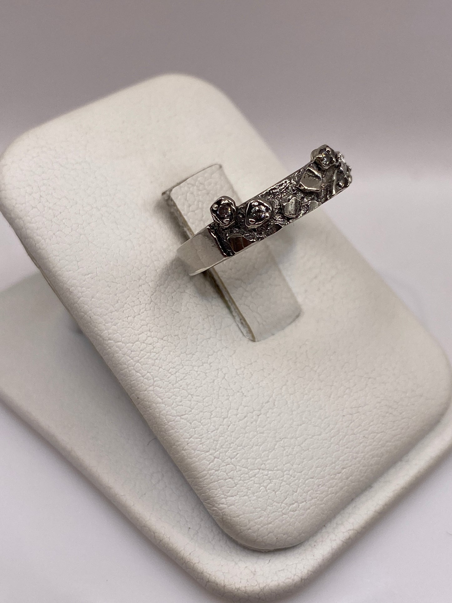 Anillo minimalista de plata .925 con piedra blanca, mostrado en dedo con piel morena
