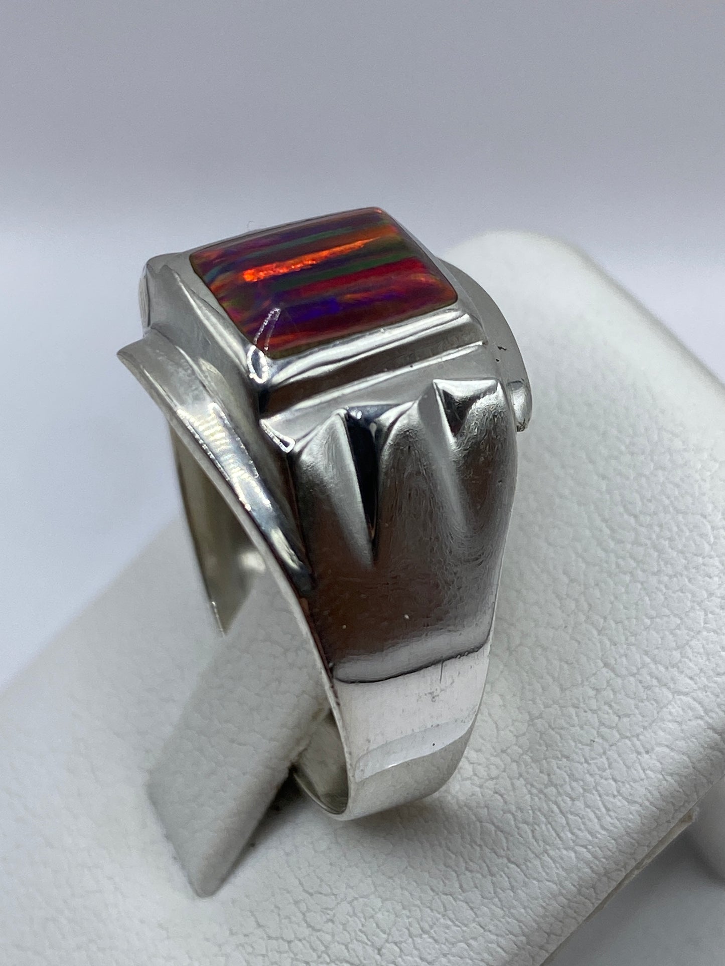 Anillo de plata de ópalo de fuego en la mano de un hombre, detalle del pulido