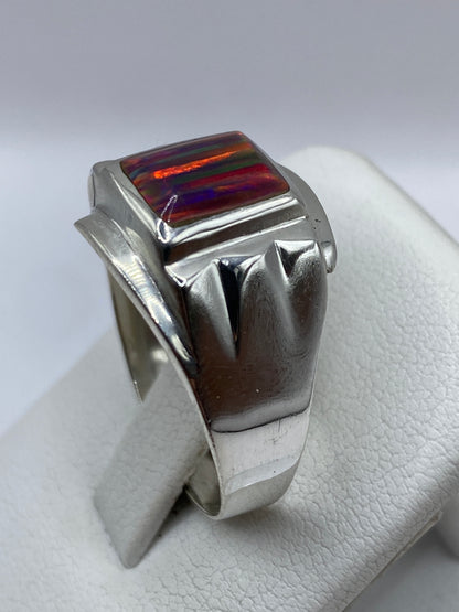 Anillo de plata de ópalo de fuego en la mano de un hombre, detalle del pulido