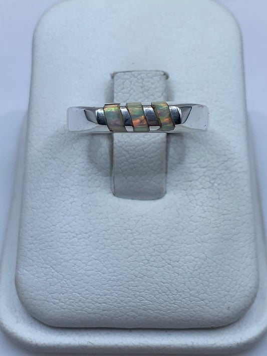 Anillo de plata con ópalo de fuego multicolor sobre blanco, mostrando el juego de colores de la piedra