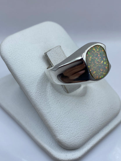 Vista frontal del anillo mostrando el juego de colores rojo, naranja y verde del ópalo