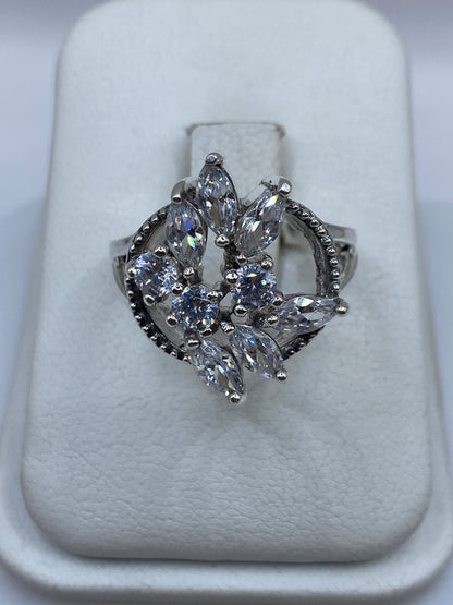 Anillo de plata escultórico con seis circonias blancas visto de frente en estuche blanco