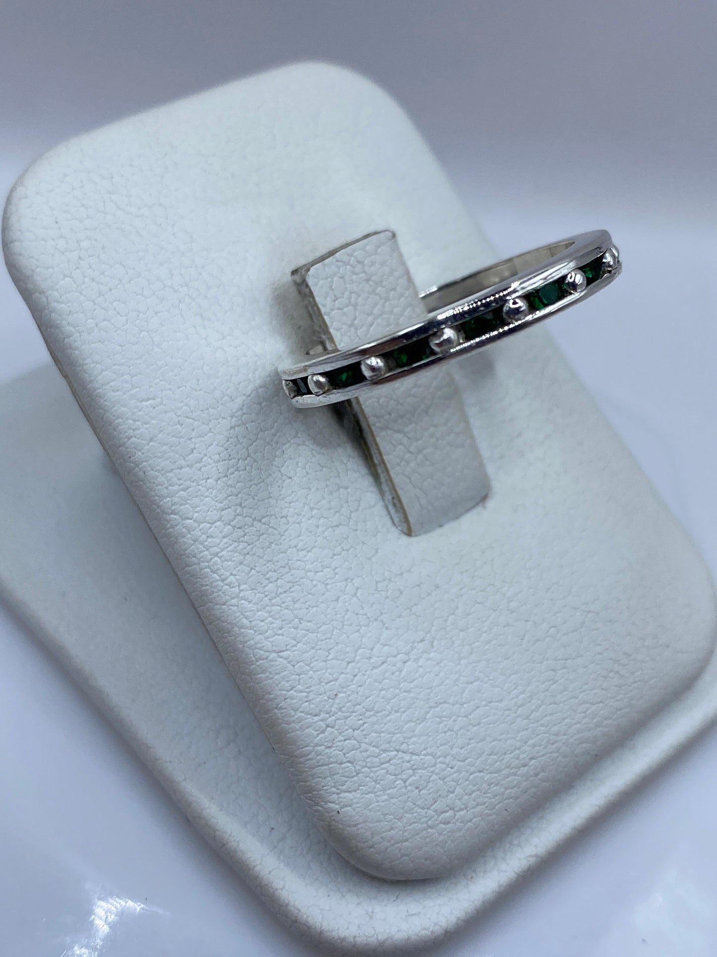 Anillo de plata con circonia verde en la mano, mostrando el brillo de la piedra