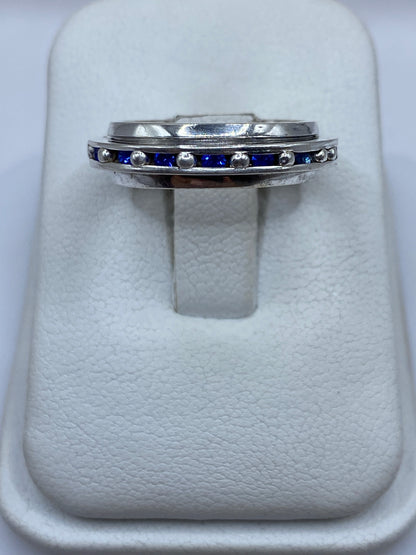 Anillo de plata con circonia azul sobre estuche blanco, vista frontal