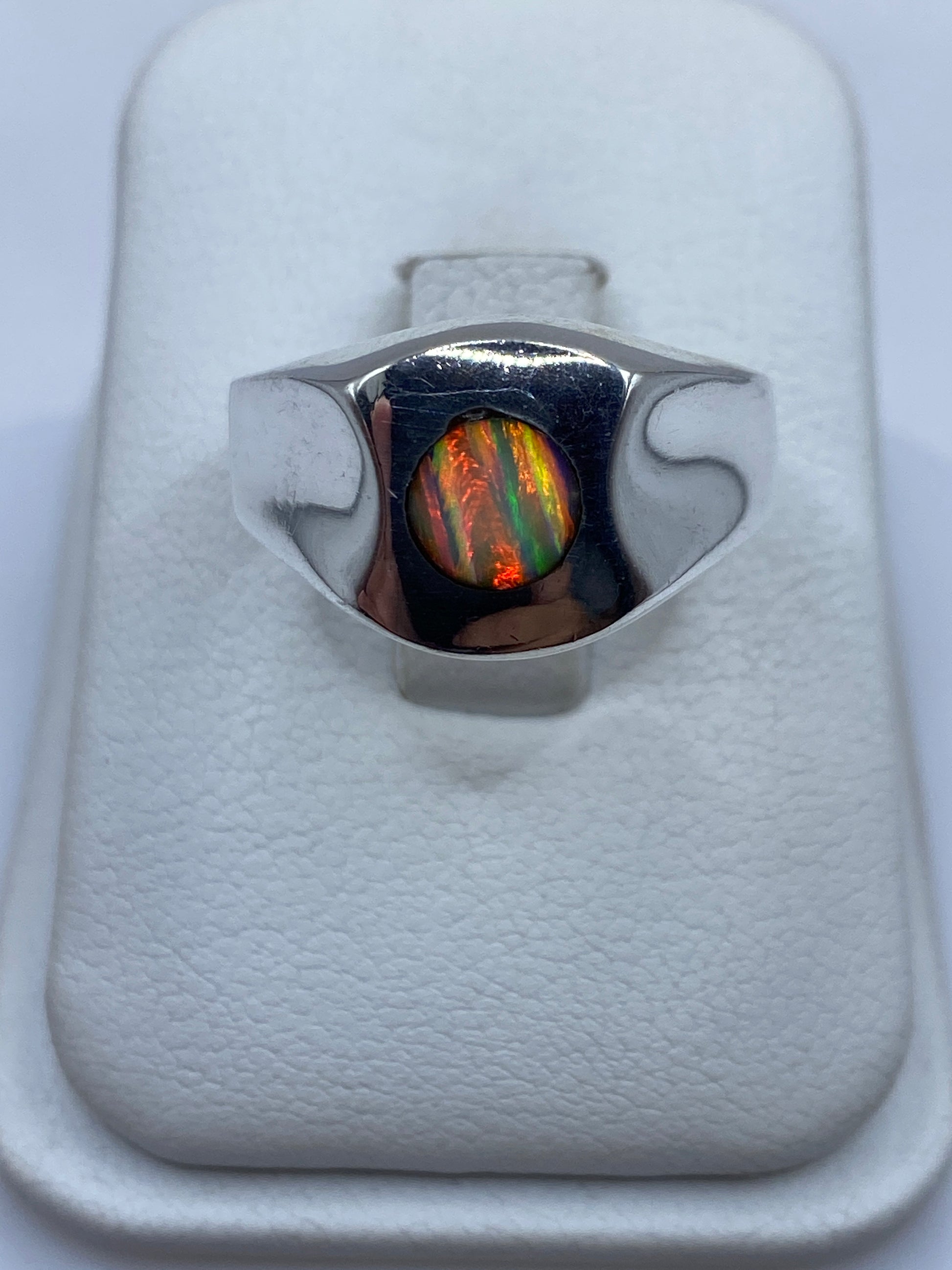 Anillo signet de plata con ópalo de fuego multicolor mostrando juego de colores rojo, naranja y verde