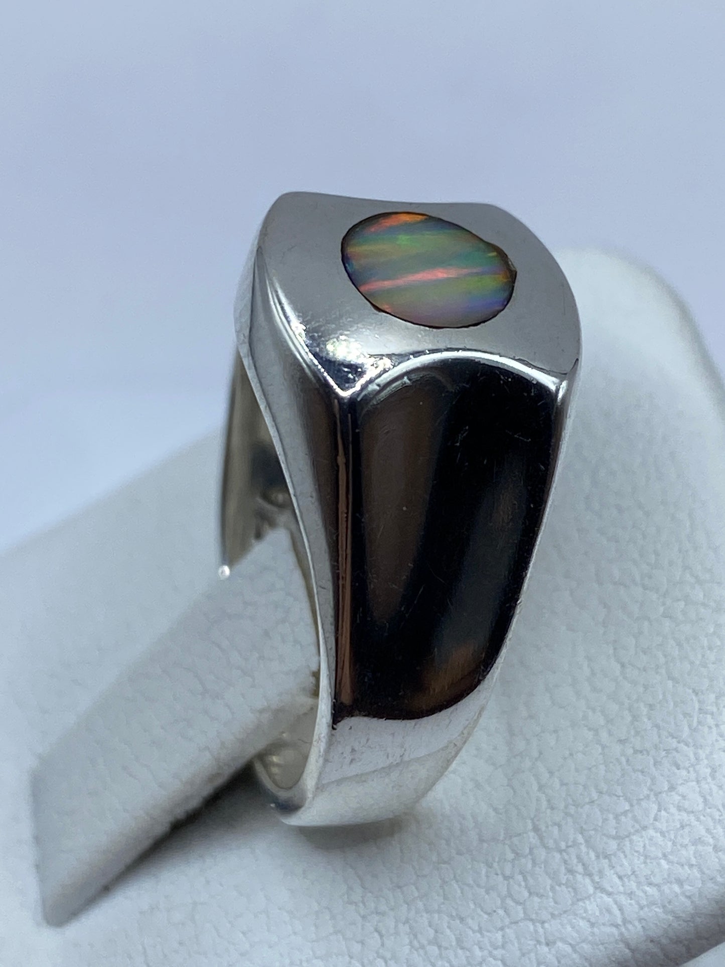 Ópalo de fuego natural en tonos multicolores dentro del bisel de plata pulida