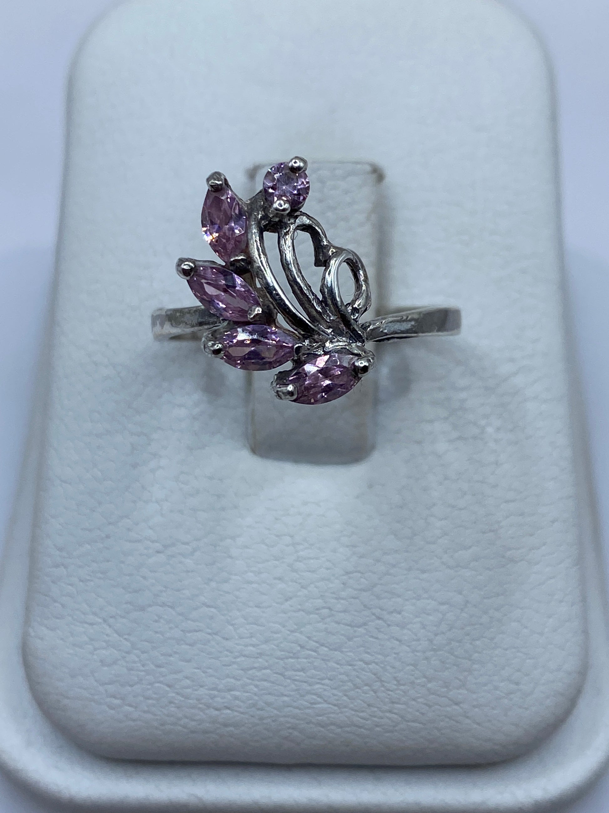 Anillo vintage de plata con circonia rosa en la mano de una mujer, mostrando el brillo de la piedra