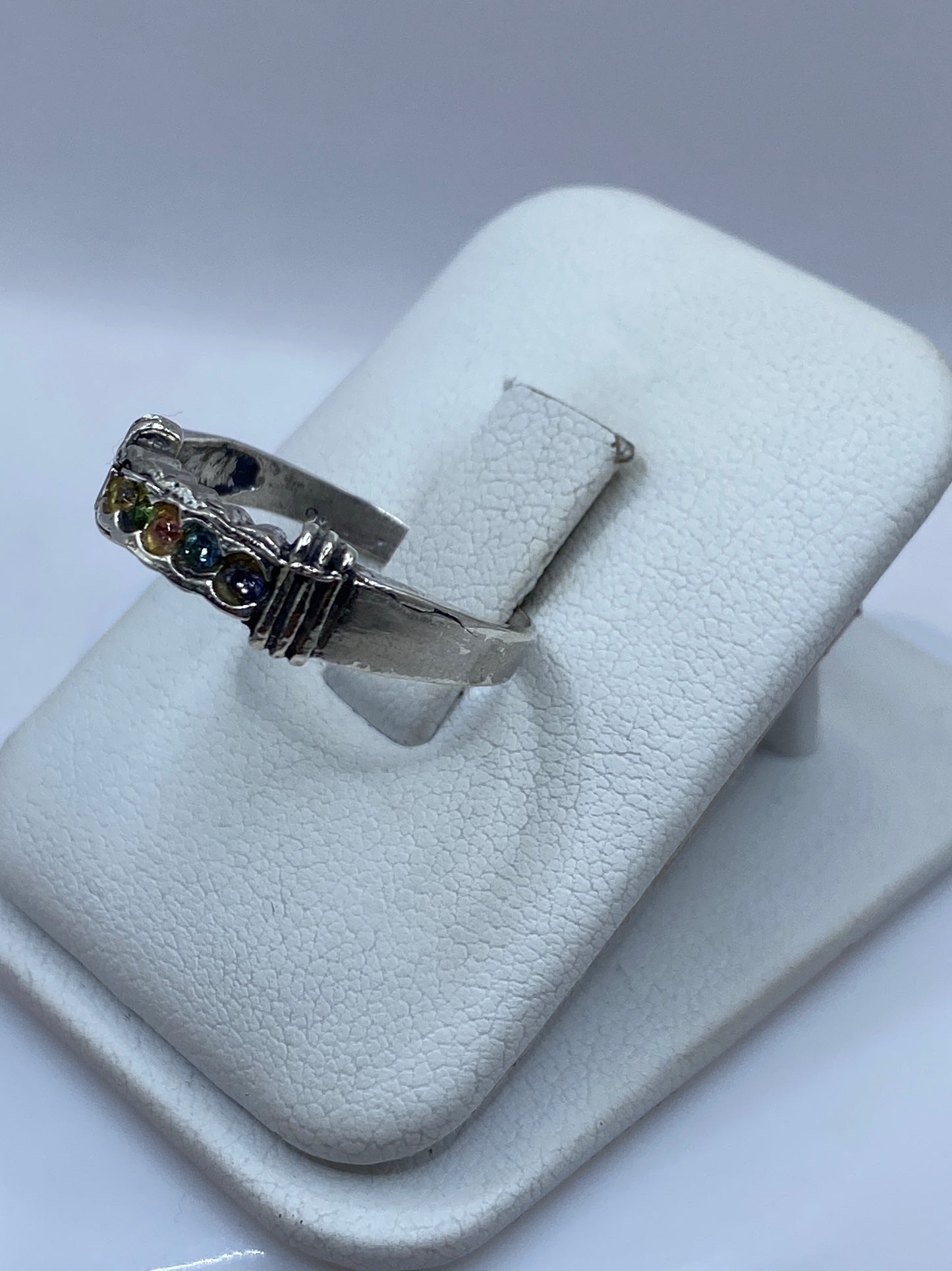 Vista frontal del anillo moderno con circonias multicolor sobre banda de plata brillante