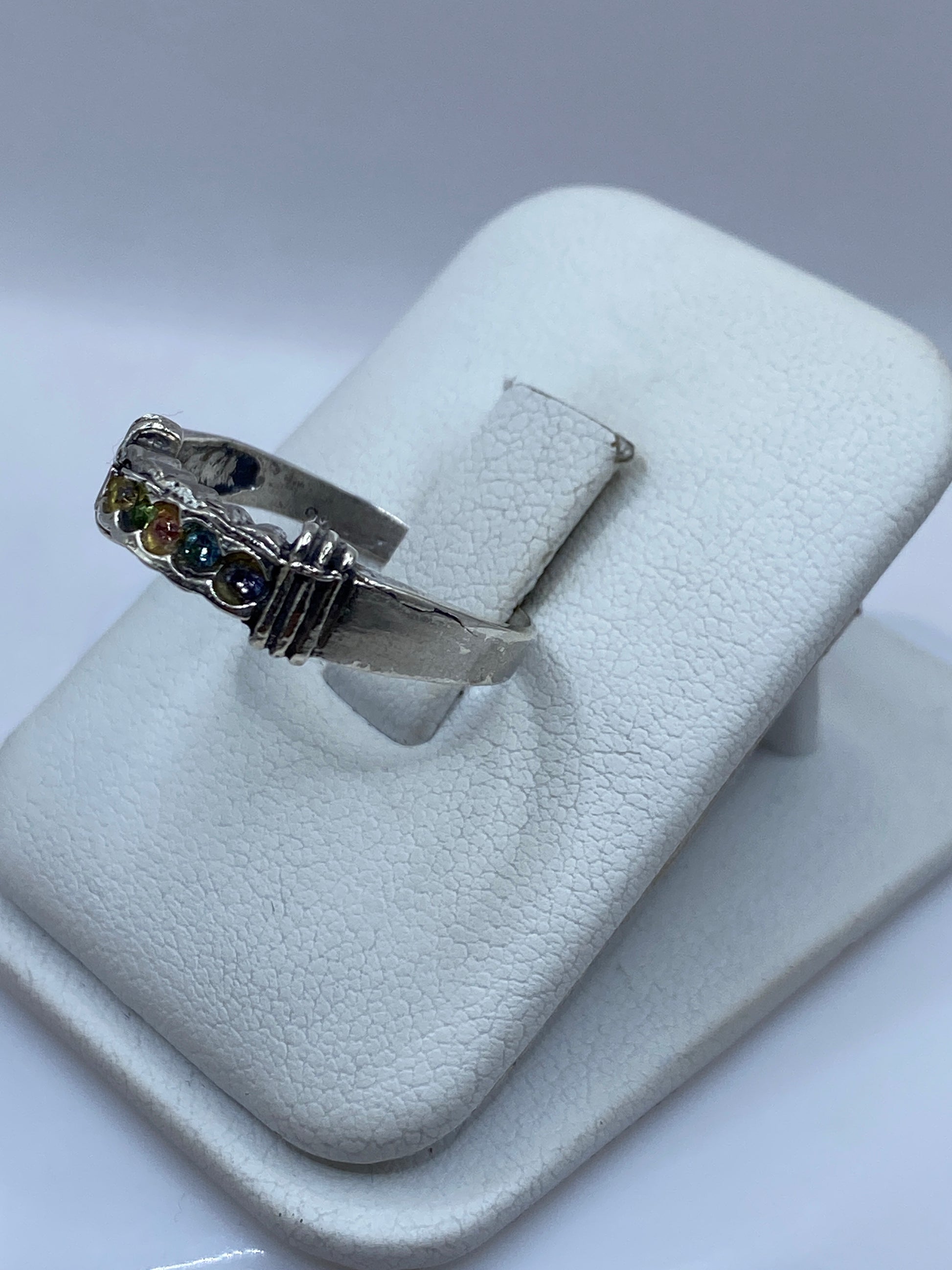 Vista frontal del anillo moderno con circonias multicolor sobre banda de plata brillante