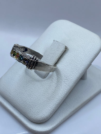 Vista frontal del anillo moderno con circonias multicolor sobre banda de plata brillante