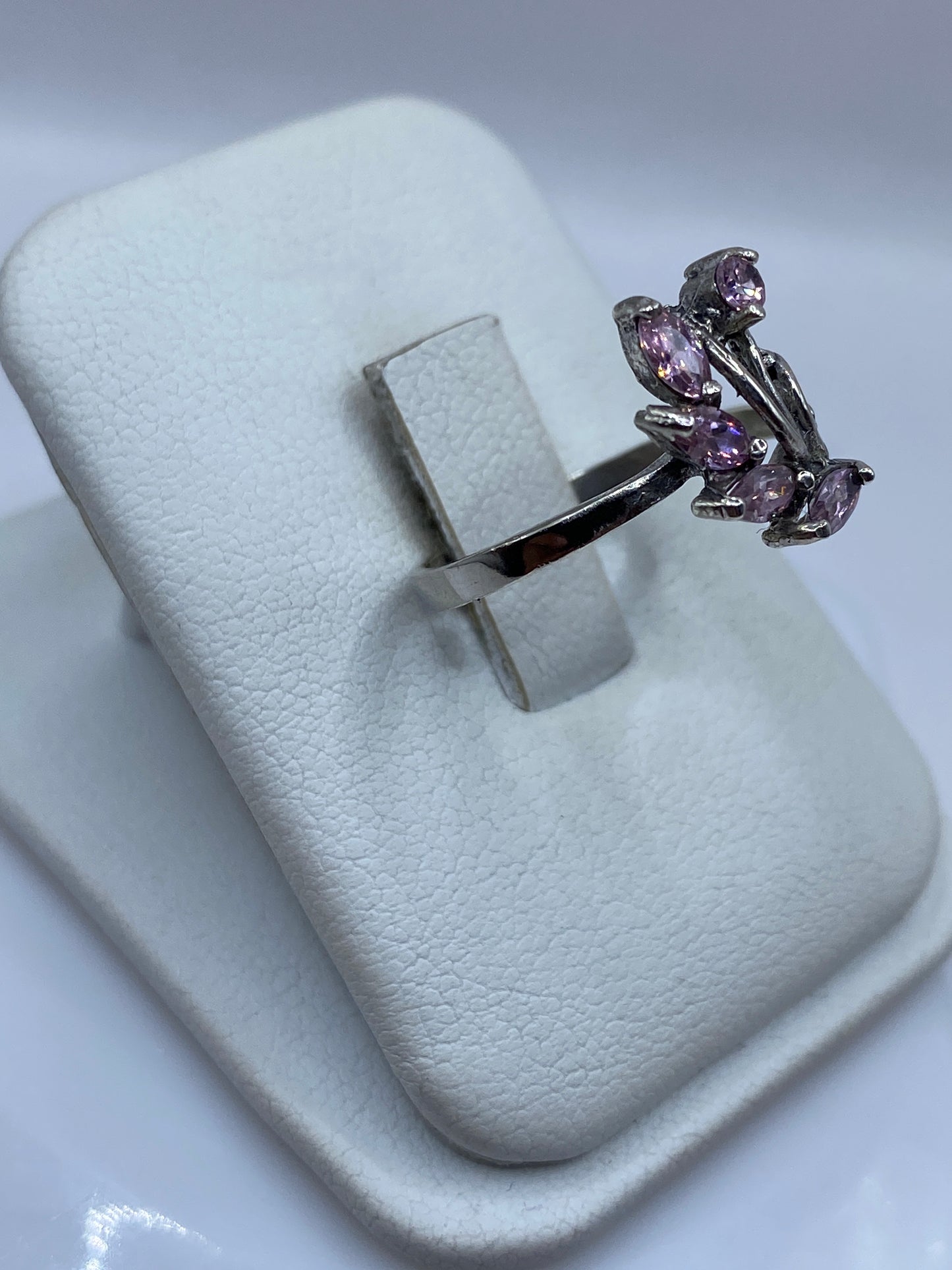 Detalle frontal del anillo mostrando el engaste floral y la piedra rosa