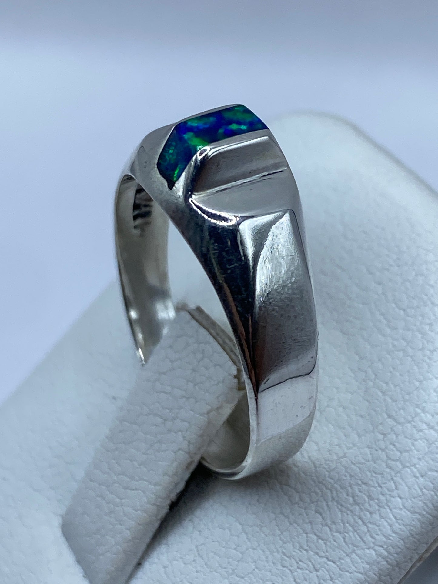 Anillo de ópalo azul en mano mostrando el juego de luz natural de la piedra