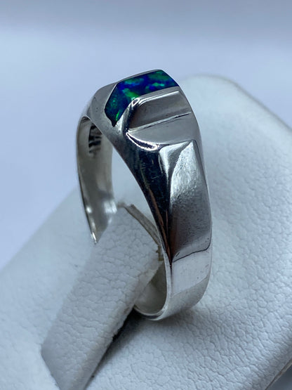 Anillo de ópalo azul en mano mostrando el juego de luz natural de la piedra