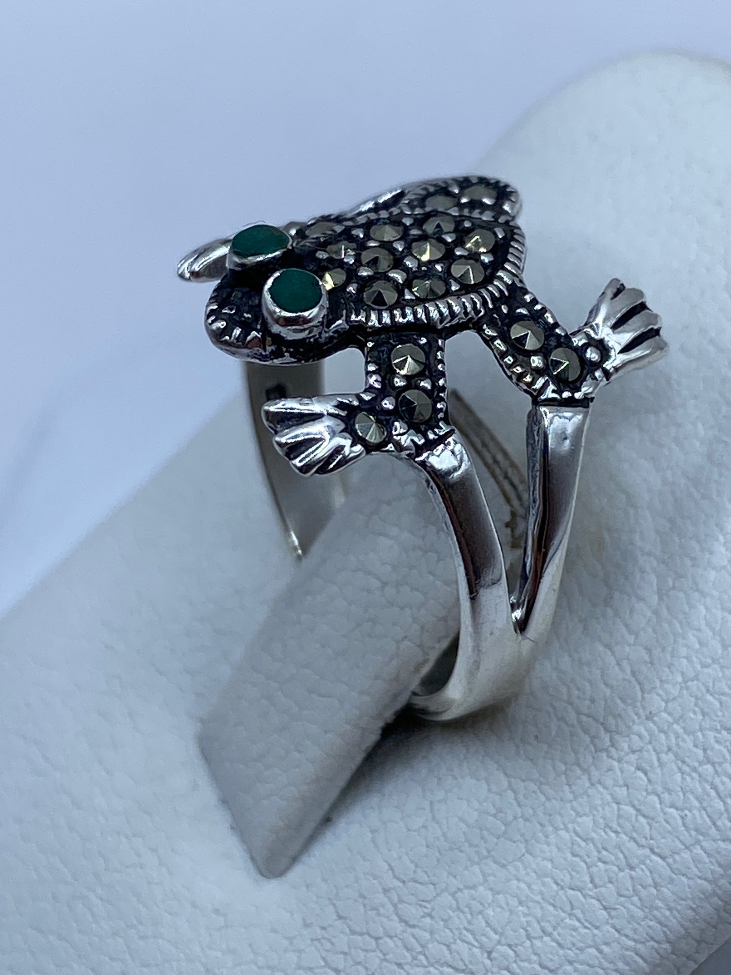 Anillo tótem en la mano mostrando textura tallada y piedra verde